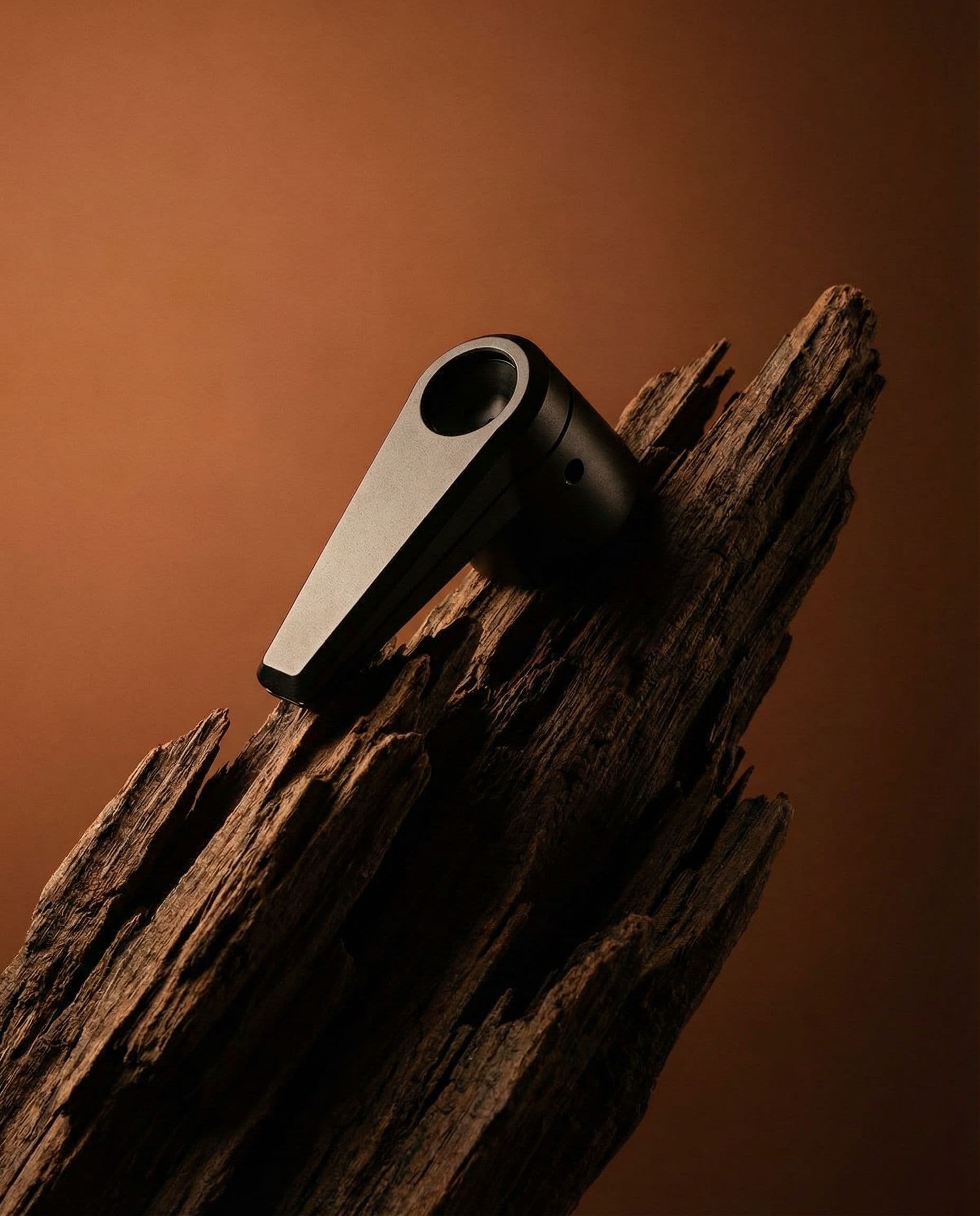 Bowlr Lit premium smoking pipe resting on natural driftwood, showcasing material contrast